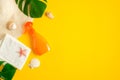 Sunscreen spray bottle on yellow background with beach hat and tropical leaves. Top view with copy space. Sun protection cosmetic