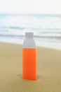 Sunscreen spray in orange bottle on the sand against the backdrop of sea waves Royalty Free Stock Photo