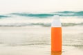 Sunscreen spray in orange bottle on the sand against the backdrop of sea waves Royalty Free Stock Photo