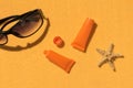 Sunscreen, starfish and sunglasses on a sandy background