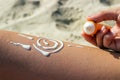 Sunscreen sun drawing lotion on suntan legs relaxing tanning on tropical beach holiday. Woman lower body lying with sunblock cream