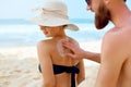 Sunscreen Sun Drawing Lotion on Suntan on Tanned Shoulder. Man Applying Protective Sun Cream on Woman Female Skin.