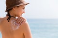 Sunscreen sunblock. Woman in a hat putting solar cream on shoulder outdoors under sunshine on beautiful summer day Royalty Free Stock Photo