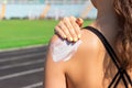 Sunscreen sunblock. Woman in a sportswear putting solar cream on shoulder on beautiful summer day. Sporty woman applying sunscreen