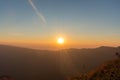 Sunset above horizon line with sun setting down behind mountains Royalty Free Stock Photo