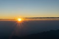 Sunset above horizon line with sun setting down behind mountains Royalty Free Stock Photo