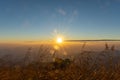 Sunset above horizon line with sun setting down behind mountains Royalty Free Stock Photo