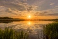 Sunset above the pond or lake with cloudy sky at summer and water reflection Royalty Free Stock Photo