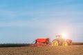 Sunset above the tractor harrowing the field Royalty Free Stock Photo