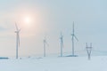 Sunset above windmill and powerlines on the field in winter Royalty Free Stock Photo