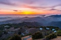 Sunset afterglow over a sea of clouds; winding road descending through rolling hills in the foreground; Mt Hamilton, San Jose,