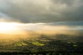 Sunset as sun beams light up the English countryside on a summers evening with dark clouds above.