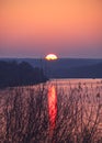 Sunset autumn landscape on a wide river with reflections and a bright sun setting beyond the horizon. Rural scene photo from high