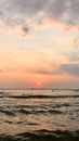 sunset in bali with a calming dark blue ocean and reflected orange skies in between the sand accompinied with her cloud friends