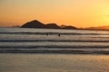 Sunset at the beach. In the background silhouettes of mountains, reddish sky. Beach with reflections in the sand. Royalty Free Stock Photo