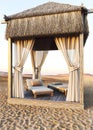 Sunset at the beach with beach bed and nature view. Large african bungalow with curtains and thatched roof. Summer