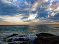 a stunning summer landscape with vast blue ocean water and a gorgeous sunset with powerful clouds and waves rolling into the beach Royalty Free Stock Photo