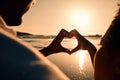 Sunset, beach and couple with a heart symbol while on a vacation, adventure or weekend trip. Romance, silhouette and