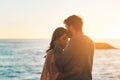 Sunset, beach and couple kiss forehead for relax, bonding and quality time on romantic date. Nature, travel and man and Royalty Free Stock Photo