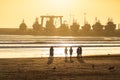 Sunset on the Beach in Essaouira Morocco with Silhouettes of People and Docked Boats Royalty Free Stock Photo