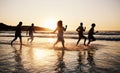 Sunset, beach and friends with freedom, running and having fun in water together on summer vacation. Ocean, silhouette Royalty Free Stock Photo