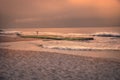 Sunset beach ocean surf waves scenery landscape with dramatic orange sunset sky and fisherman Royalty Free Stock Photo