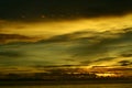 Sunset at the beach by the pier on a cloudy romantic day Royalty Free Stock Photo