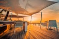 Sunset beach restaurant, sunset light and soft colors on wooden deck with white furniture and sea view Royalty Free Stock Photo