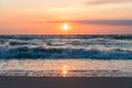 Sunset at the beach with sand and waves in the forground and reflection in the shallow water Royalty Free Stock Photo