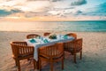 Beach dinner set-up for couples or honeymooners. Sunset beach scene with wooden table and chairs ready for dinner Royalty Free Stock Photo