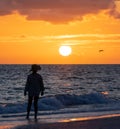 Sunset on the beach with silhouette of a woman and flying bird Royalty Free Stock Photo