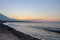 Sunset on the beach on a tropical island. Orange colored sky and clouds. Big majestic volcano on the horizon. Quiet sea. Royalty Free Stock Photo