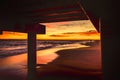 Sunset at beach under a pier Royalty Free Stock Photo