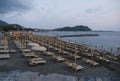 sunset on the beach with yellow sunbeds over the sea and horizon and hills with hotels. Sestri Levante, Liguria, Italy Royalty Free Stock Photo