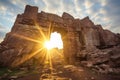 sunset beams piercing through a ruined stone arch
