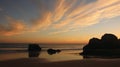 Sunset behind big cliffs at deserted beachSunset sky and moving clouds at beach Royalty Free Stock Photo