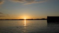 Sunset behind horizon with reflection and glitter on lake