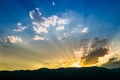 Sunset behind mountain with beautiful sunbeam through the cloud Royalty Free Stock Photo