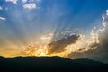 Sunset behind mountain with beautiful sunbeam through the cloud Royalty Free Stock Photo