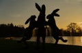 Sunset behind silhouetted dancing hares sculpture. Wisley.