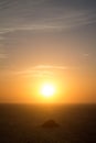 Sunset with big sun and rock in the middle of the sea.