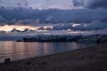 Sunset with blue dark clouds in sky in bay of lake Baikal with jetty mole pier with old ships and boats, evening sea, reflection Royalty Free Stock Photo