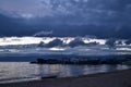 sunset with blue dark clouds in sky in bay of lake Baikal with jetty pier with old ships and boats, evening sea, reflection Royalty Free Stock Photo