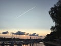 Sunset, boat, dock, plane and condensation trail.