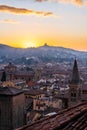 Sunset in Bologna, aerial view of rooftops and hill with San Luca Monastery.