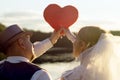 Sunset, the bride and bridegroom holding heart