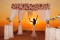 Sunset. bride silhouette. Wedding ceremony arch with flower arrangement and white curtain on cliff above sea, outdoor photo.