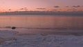 Sunset in a calm sea with frozen seashore.