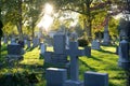 Sunset at the cemetery. Graveyard, tombstones in green area of trees and grass during fall season Royalty Free Stock Photo