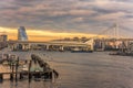 Sunset on the circular highway leading to the Rainbow Bridge with Cargo and cruise ships moored or sailing in Odaiba Bay of Tokyo